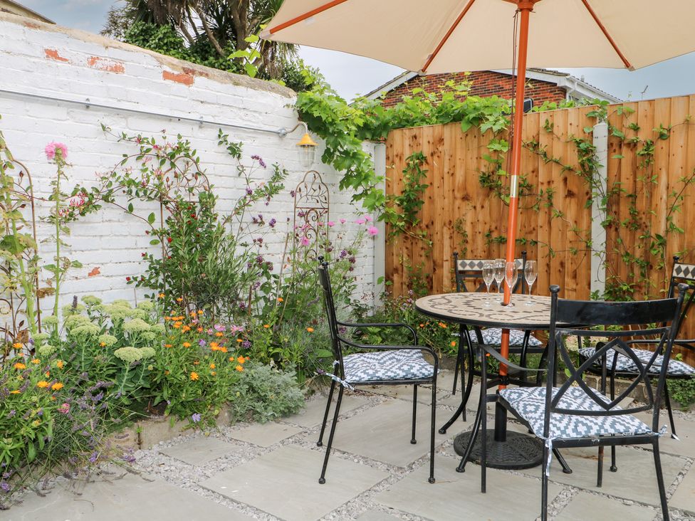 A garden with a table, chairs and flowers at Lower Floor Flat