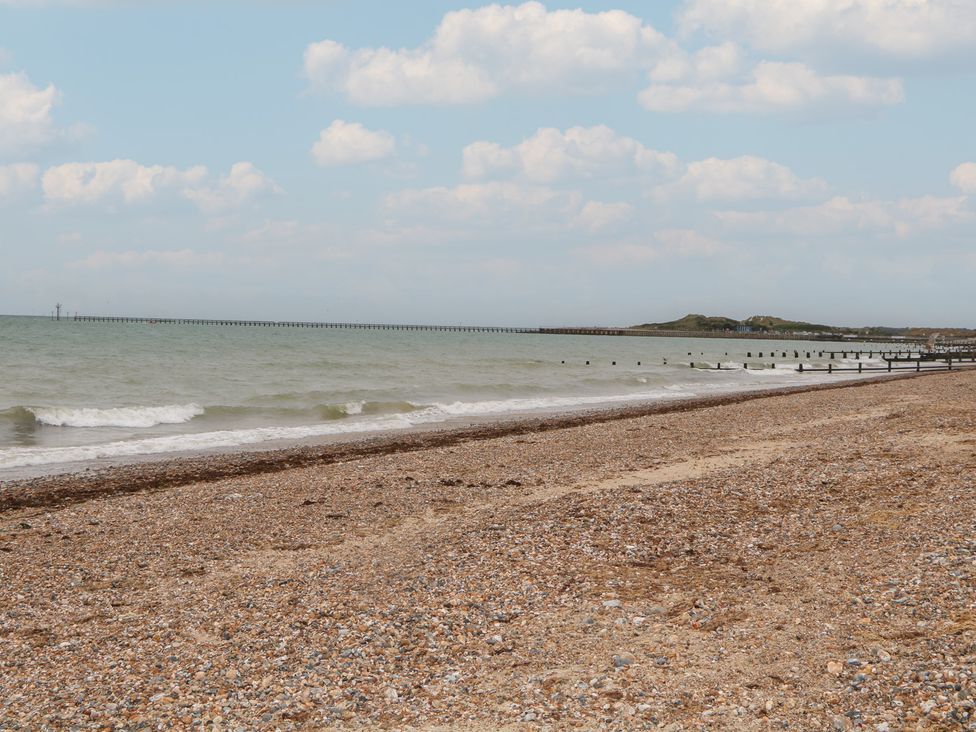 A beach with waves and a pier in the distance at Lower Floor Flat