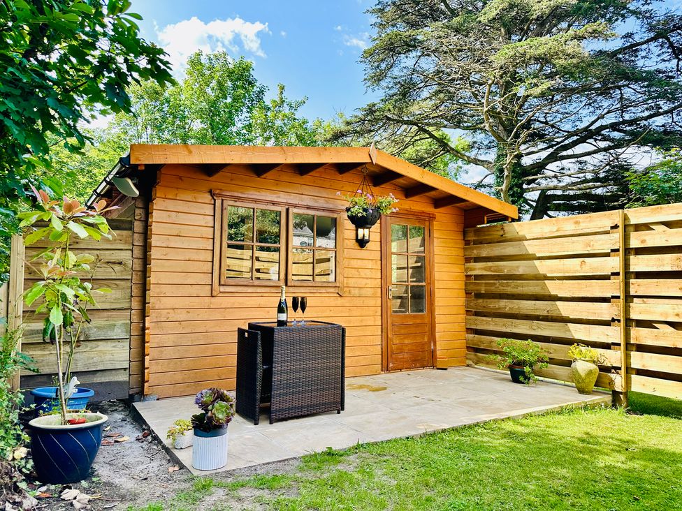 A garden shed with a table and chairs at Harvey's Lodge in Helston
