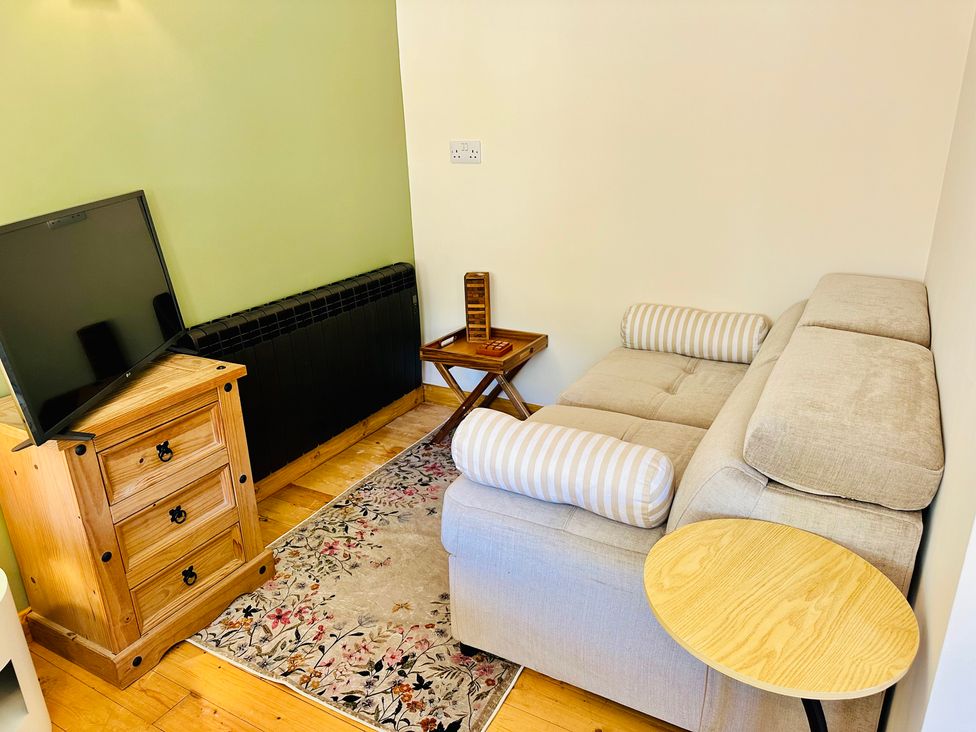 A living room with a sofa and television at Harvey's Lodge in Helston