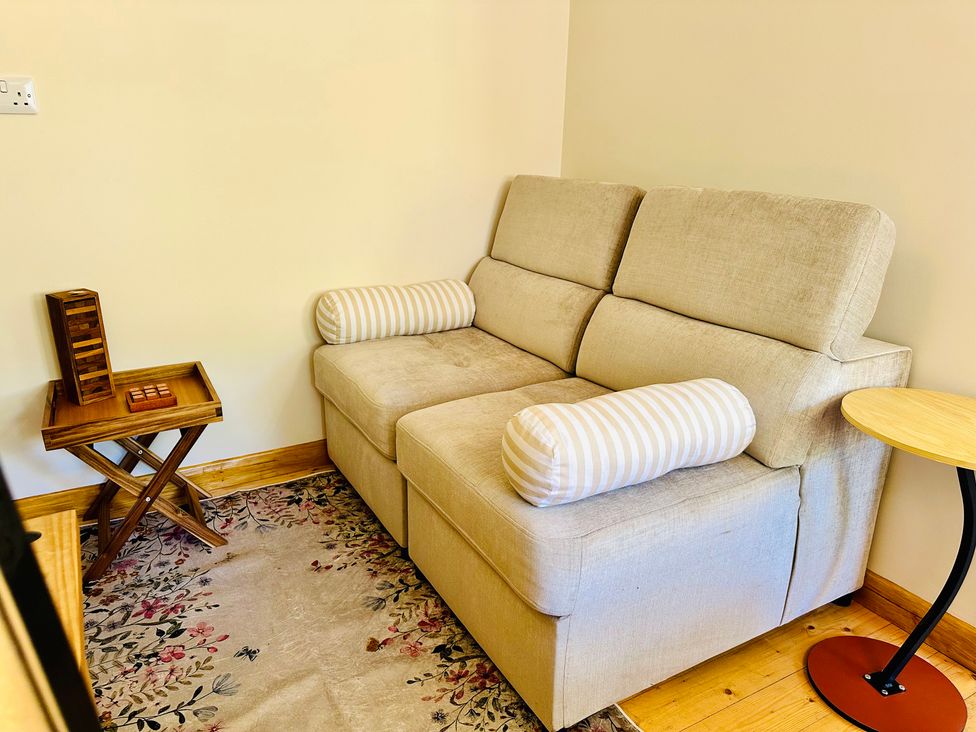 A sofa with cushions beside a side table and game board at Harvey's Lodge in Helston