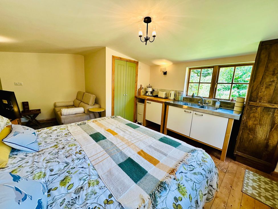A bedroom with a bed and kitchen unit at Harvey's Lodge in Helston