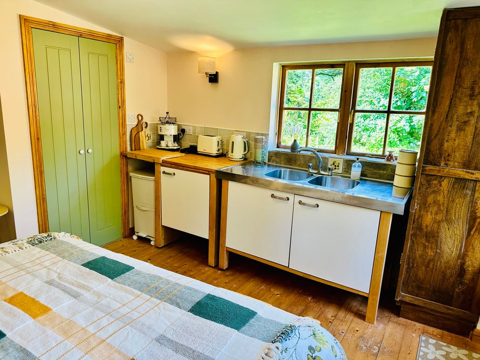 A kitchen with cabinets, sink, kettle, and coffee maker at Harvey's Lodge in Helston