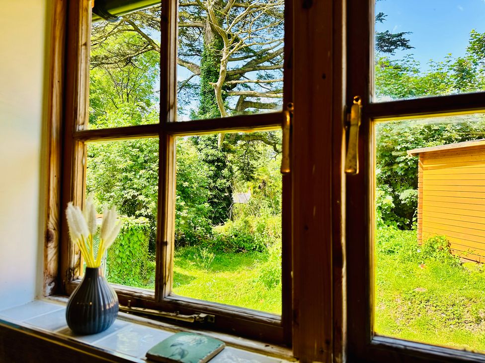 A view of a garden with greenery and a shed from a window at Harvey's Lodge in Helston
