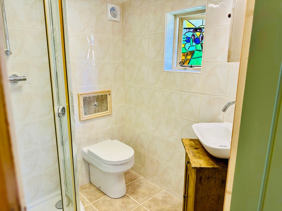 A bathroom with a shower, toilet, and sink at Harvey's Lodge in Helston
