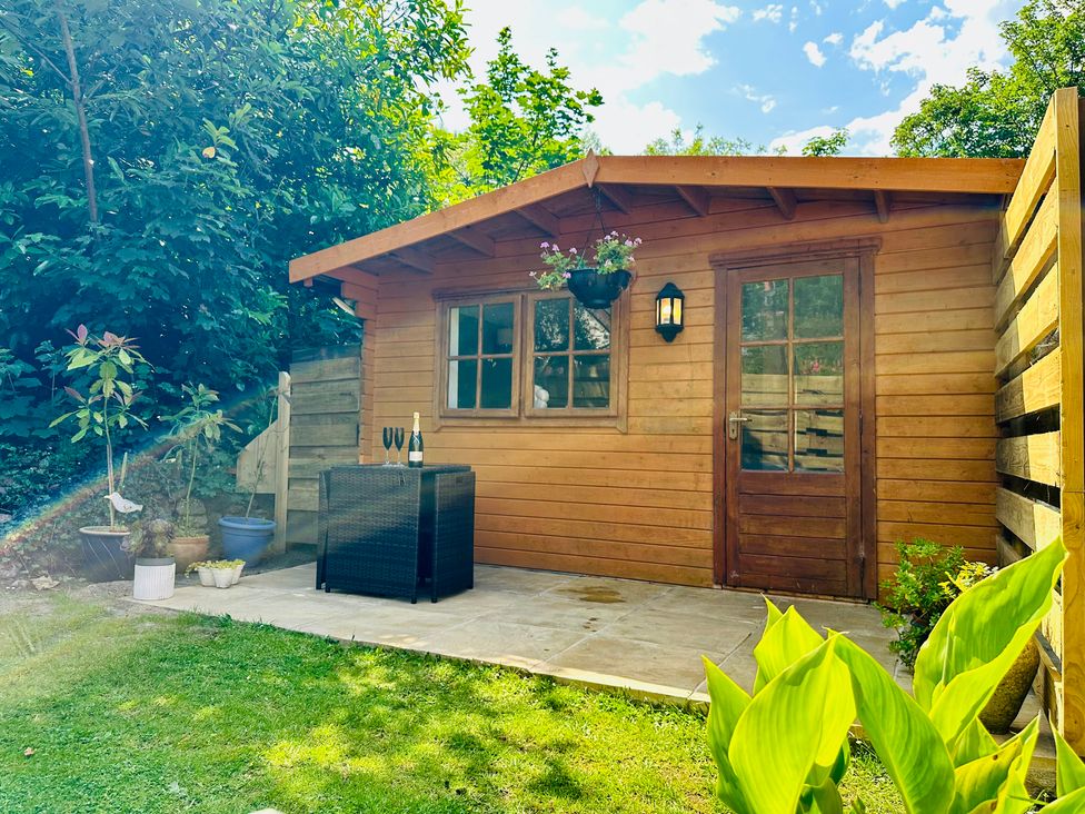 A shed with plants and a table in the garden at Harvey's Lodge in Helston