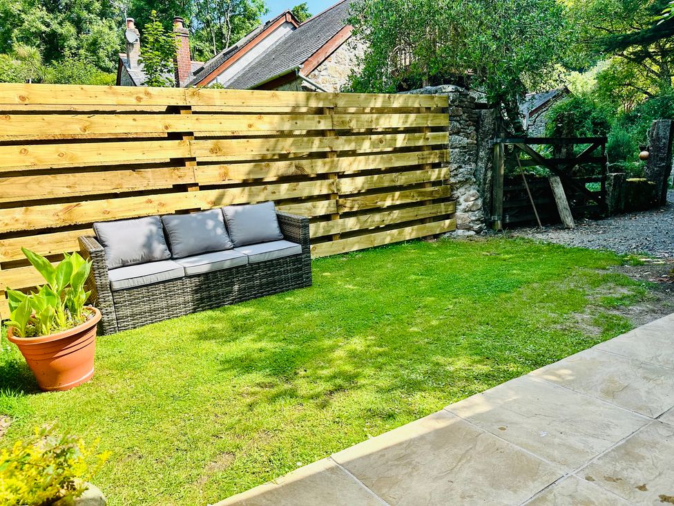 A garden with a seating area and a potted plant at Harvey's Lodge in Helston