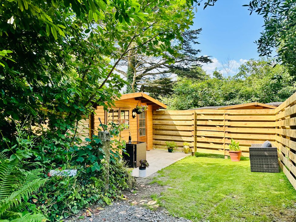 A garden with a shed and potted plants at Harvey's Lodge in Helston