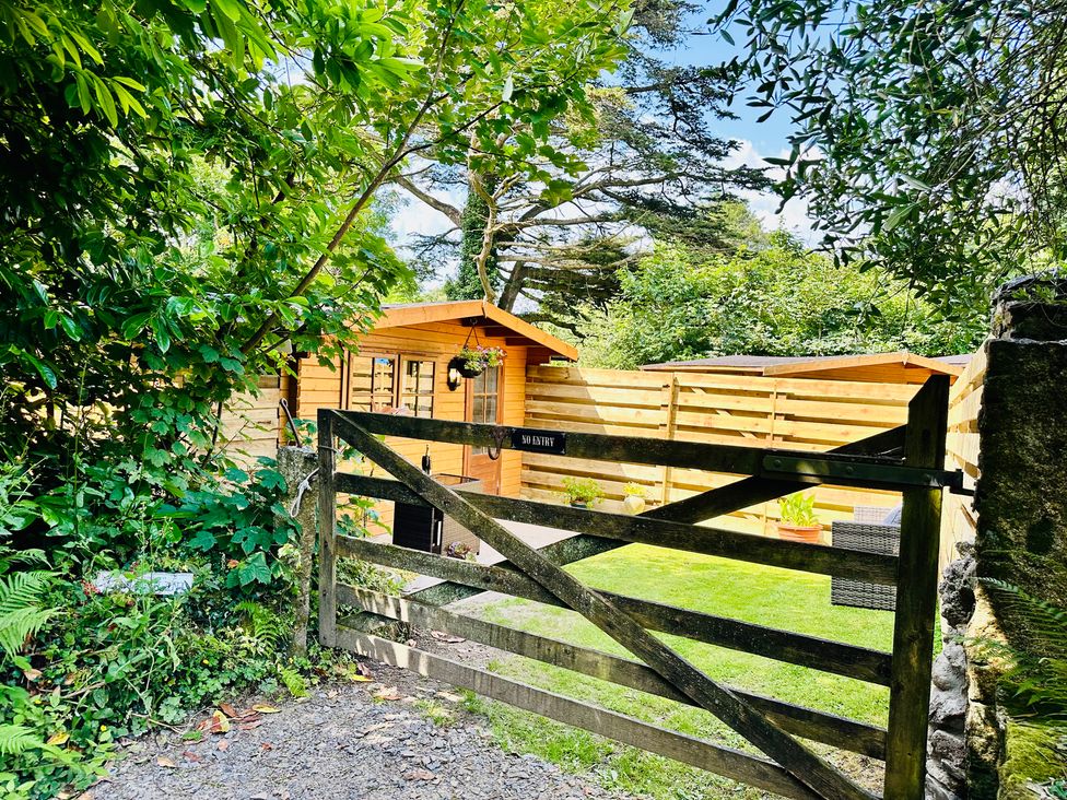 A garden with a wooden gate and a cabin at Harvey's Lodge in Helston