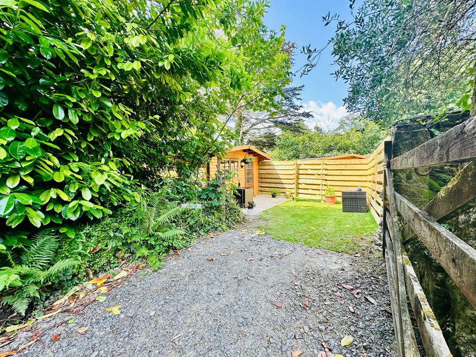 A garden with a wooden shed and pathway at Harvey's Lodge in Helston
