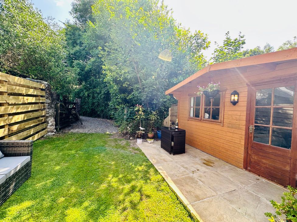 A garden with a shed and seating area at Harvey's Lodge in Helston