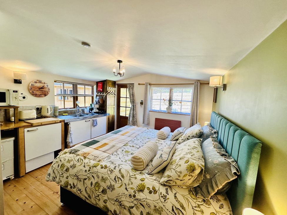 A studio apartment with a bed and kitchenette at Harvey's Lodge in Lowertown, Helston