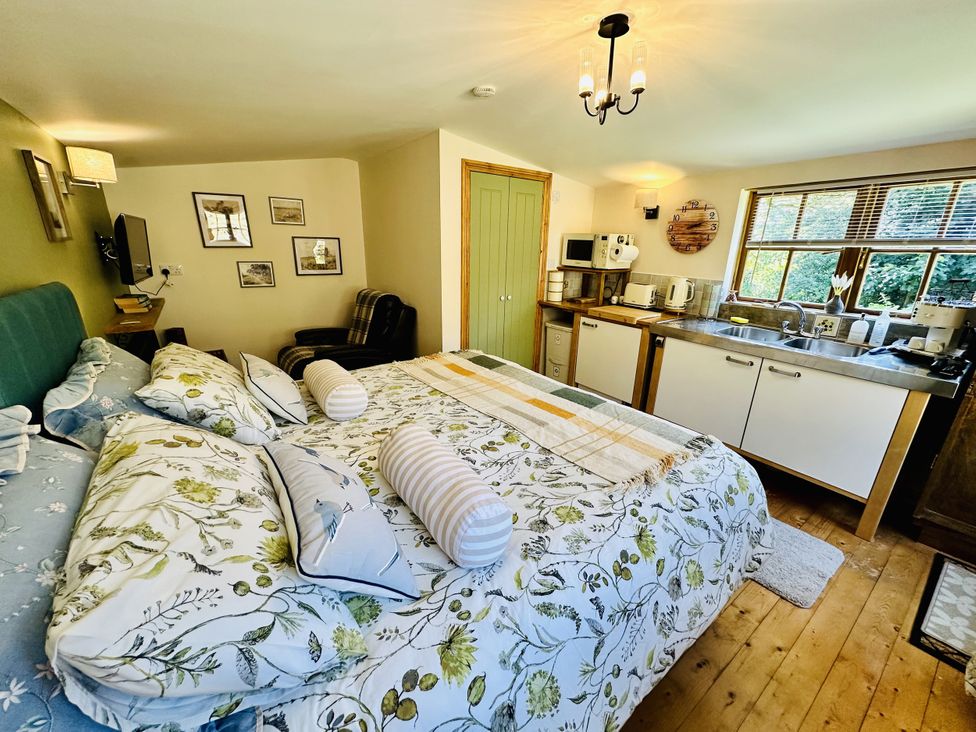 A bedroom with a kitchenette and a bed at Harvey's Lodge in Lowertown, Helston