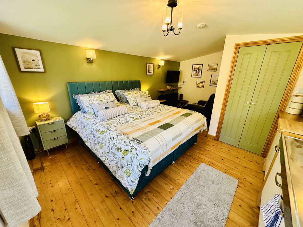 A bedroom with a bed and bedside table at Harvey's Lodge in Lowertown, Helston