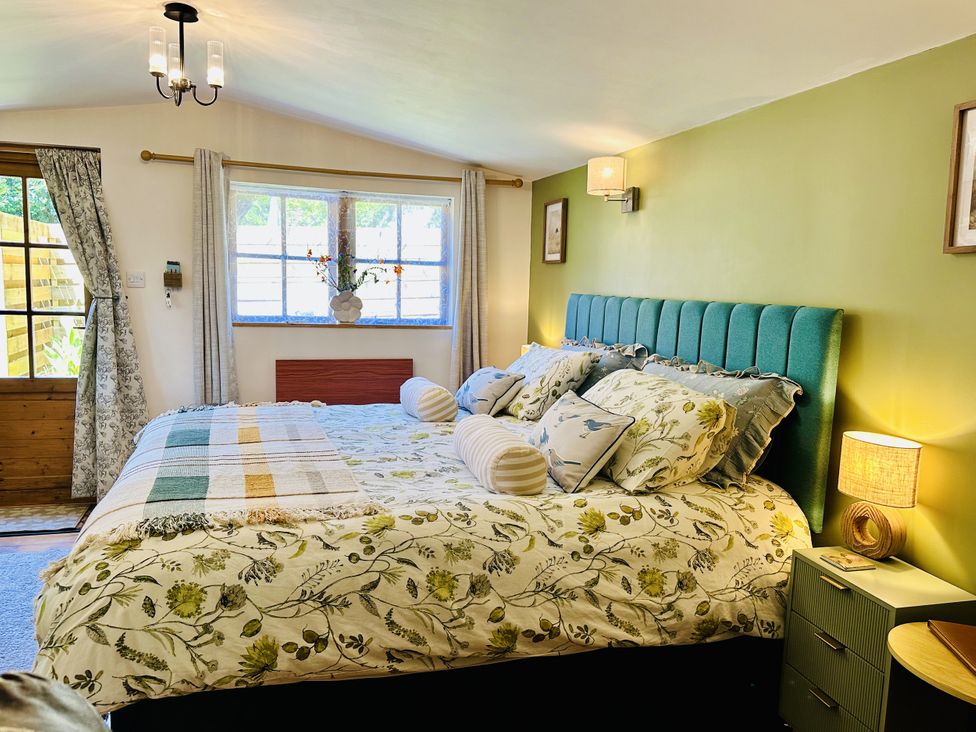 A bedroom with a bed and window at Harvey's Lodge in Lowertown, Helston