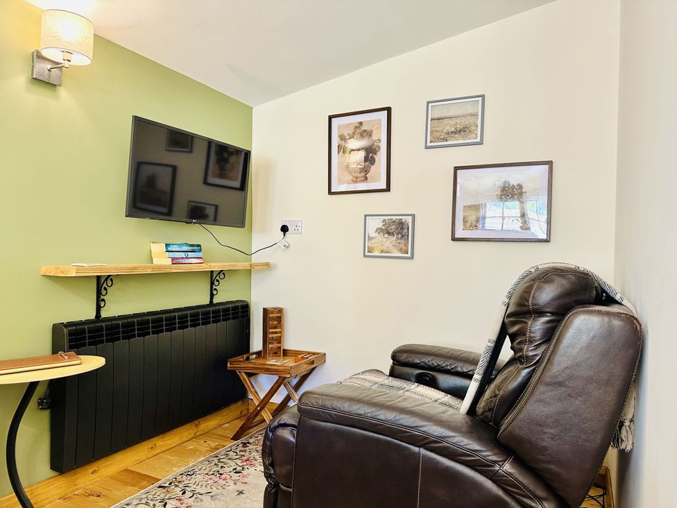 A living room with a television and a recliner chair at Harvey's Lodge in Lowertown, Helston