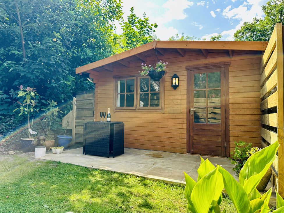 A shed with patio furniture in a garden at Harvey's Lodge in Lowertown, Helston