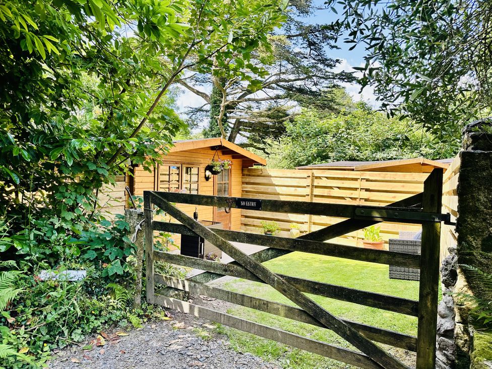 A wooden cabin behind a gate in an outdoor area at Harvey's Lodge, Lowertown, Helston