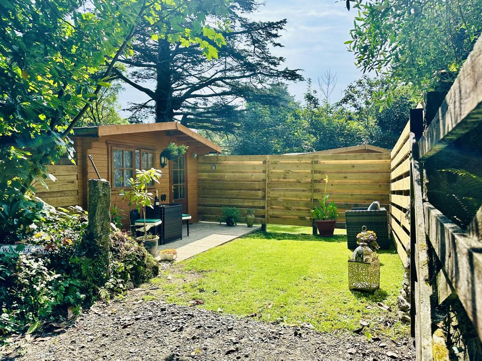 A garden with a wooden cabin and potted plants at Harvey's Lodge in Lowertown, Helston