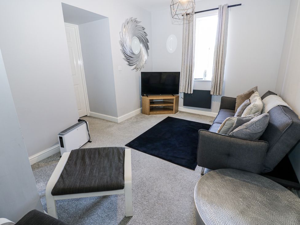 A living room with a television and sofa at Lowther House Whitehaven