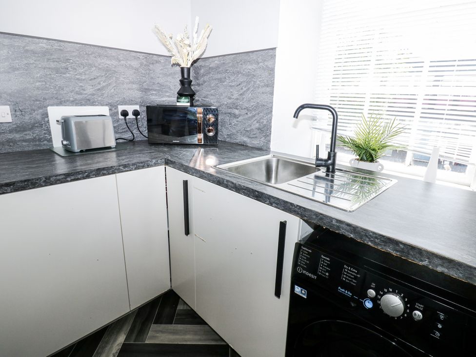 A kitchen with sink, toaster, microwave and washing machine at Lowther House in Whitehaven
