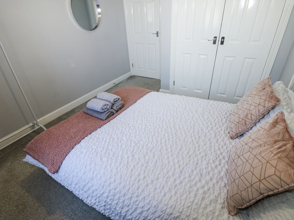 A bedroom with a bed and towels folded on it at Lowther House in Whitehaven