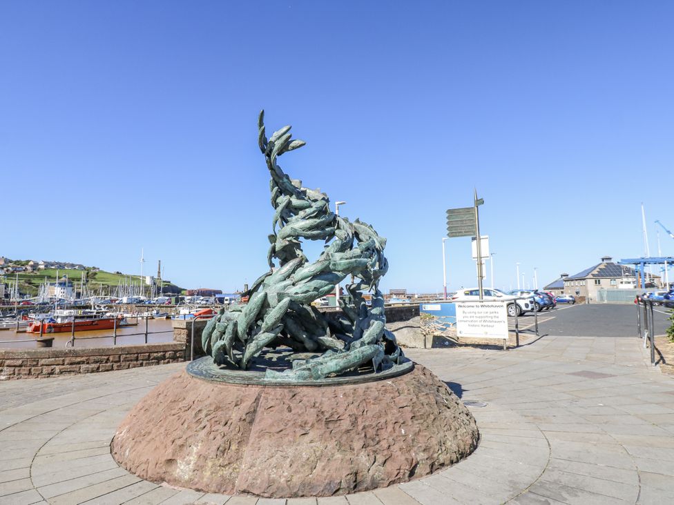 A sculpture at a marina with fishing boats in the background at Lowther House Whitehaven