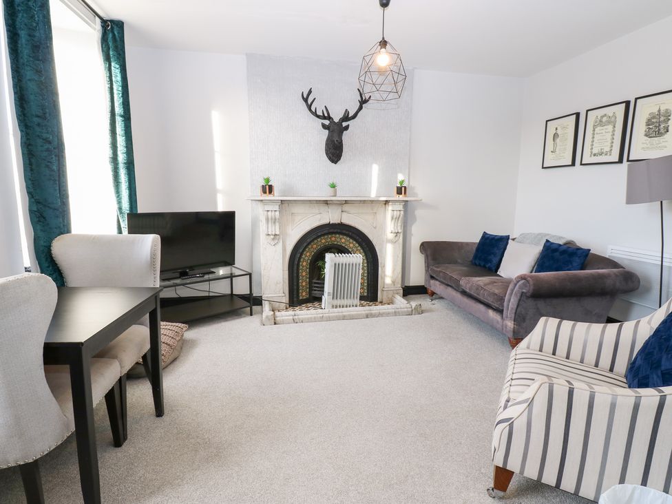 A living room with a fireplace and television at Lowther Apartment in Whitehaven