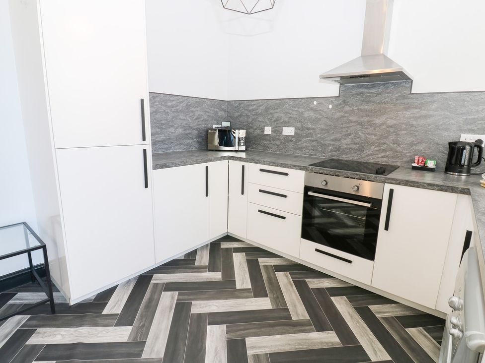 A kitchen with cabinets and appliances at Lowther Apartment in Whitehaven