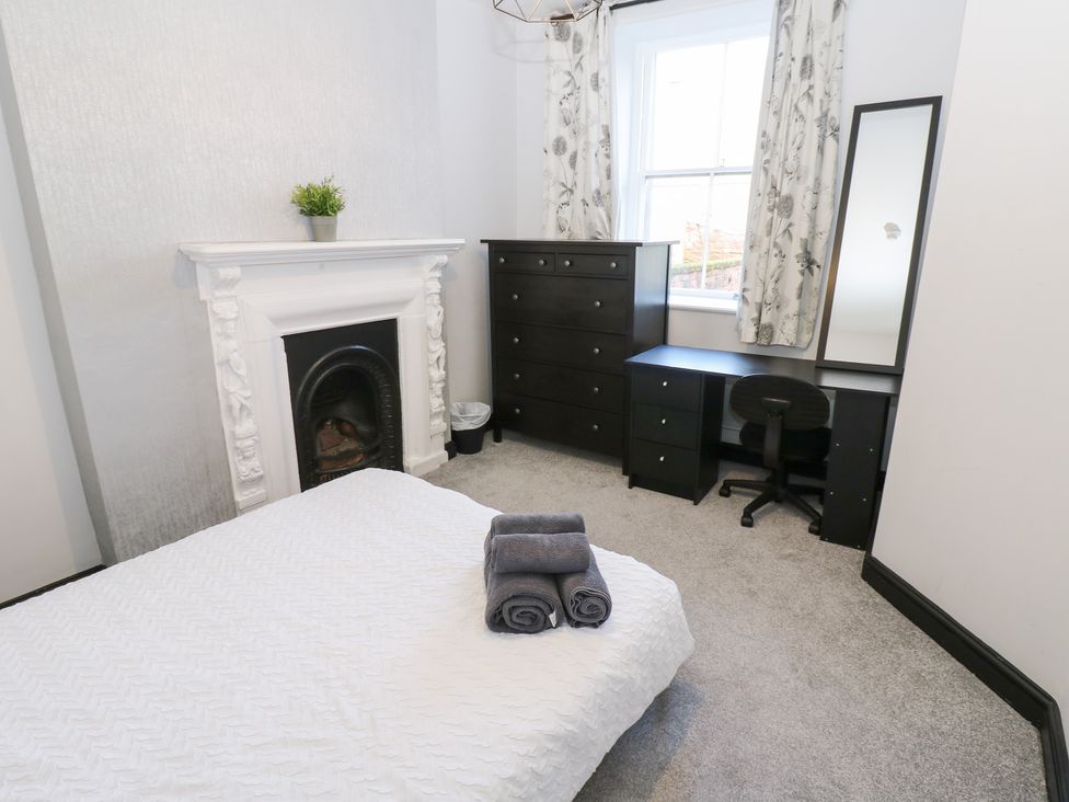 A bedroom with a bed and dresser at Lowther Apartment in Whitehaven