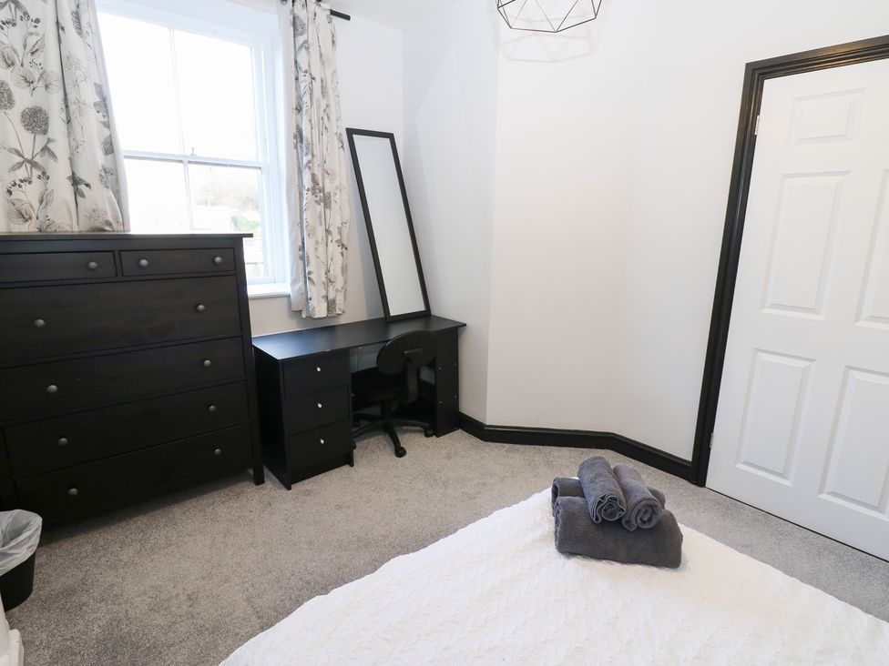 A bedroom with a dresser, desk, and towels in Lowther Apartment Whitehaven