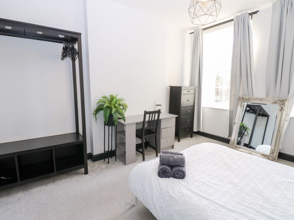 A bedroom with a bed, desk, dresser, and mirror at Lowther Apartment in Whitehaven