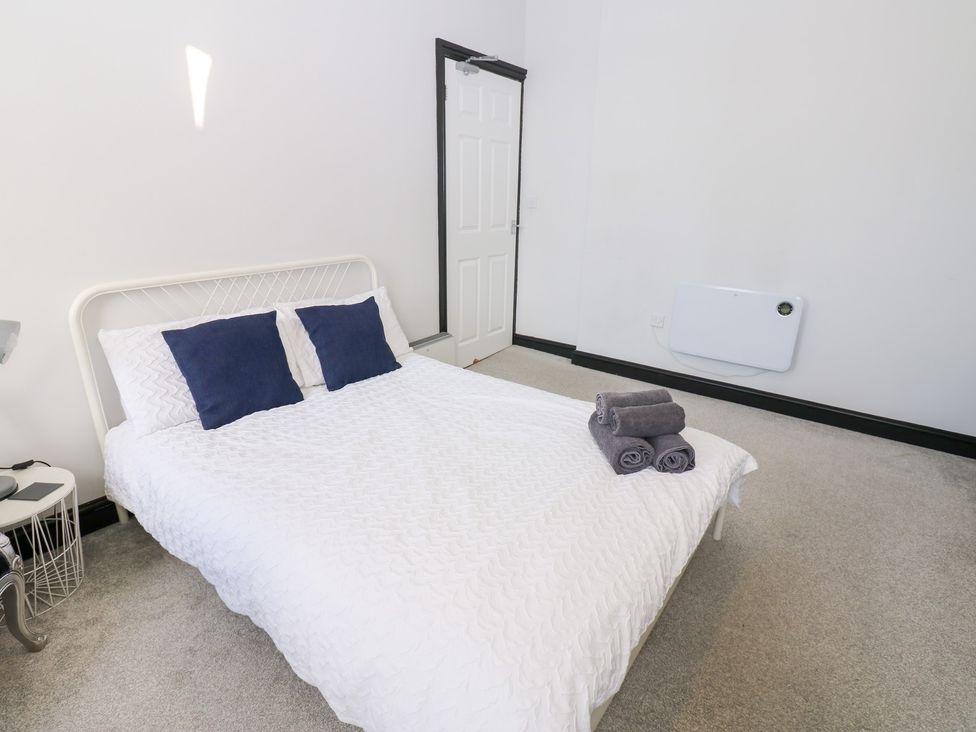 A bedroom with a bed and towels at Lowther Apartment in Whitehaven