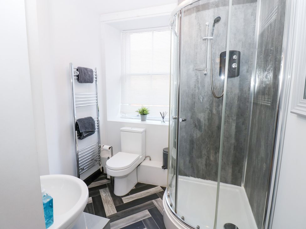 A bathroom with a shower, sink, and towel rail at Lowther Apartment in Whitehaven