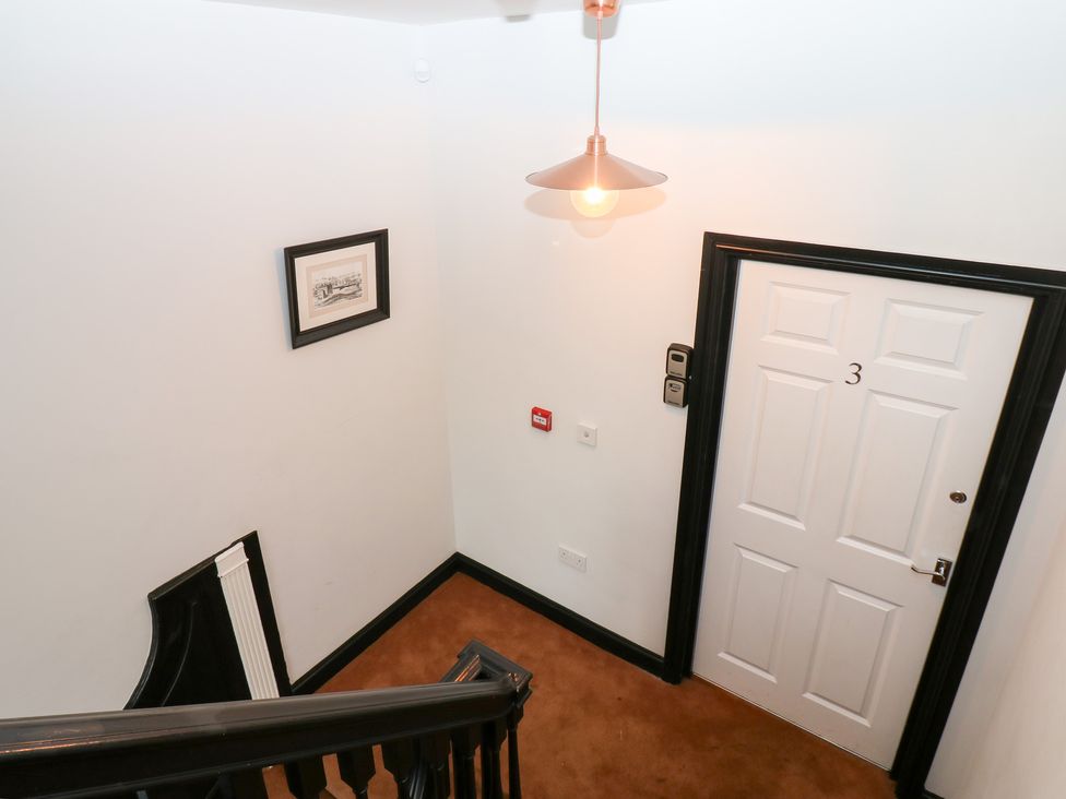 A staircase and door in a hallway at Lowther Apartment in Whitehaven