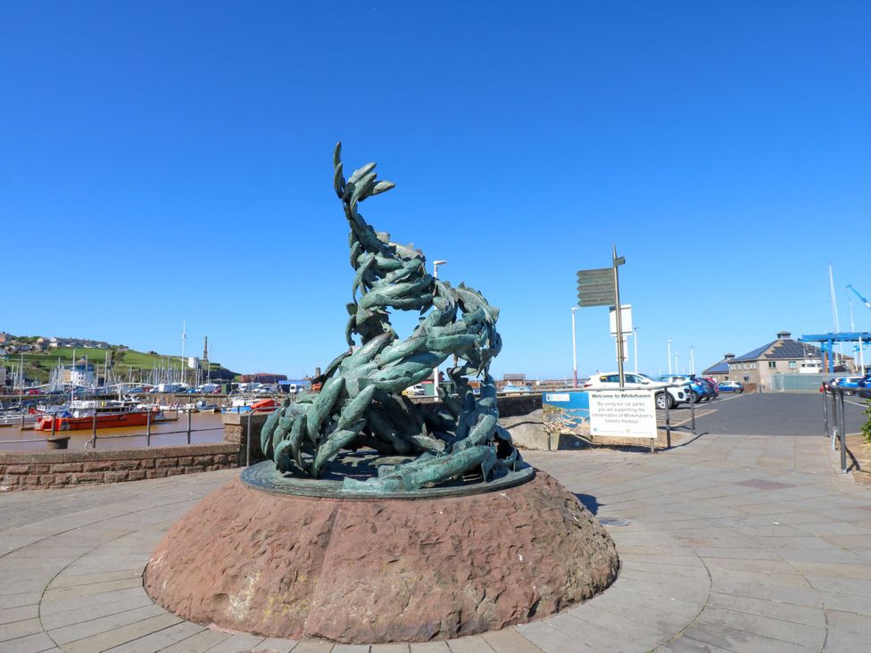 A sculpture in a harbor area with boats and a signpost at Lowther Penthouse in Whitehaven