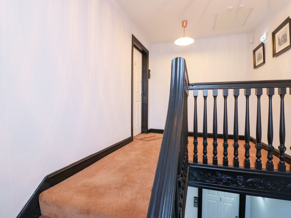 A hallway with a staircase and doors at Lowther Penthouse in Whitehaven