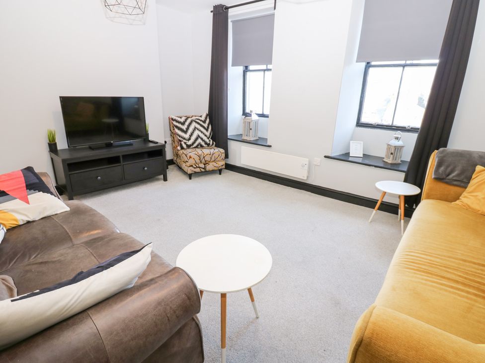 A living room with a television and seating arrangements at Lowther Penthouse in Whitehaven