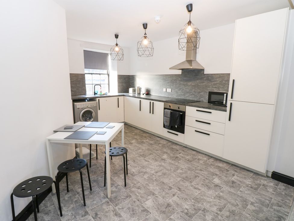 A kitchen with appliances and table at Lowther Penthouse in Whitehaven