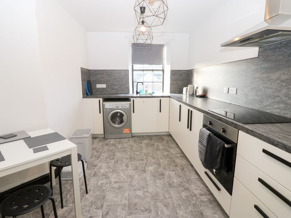 A kitchen with a washing machine and a table at Lowther Penthouse in Whitehaven
