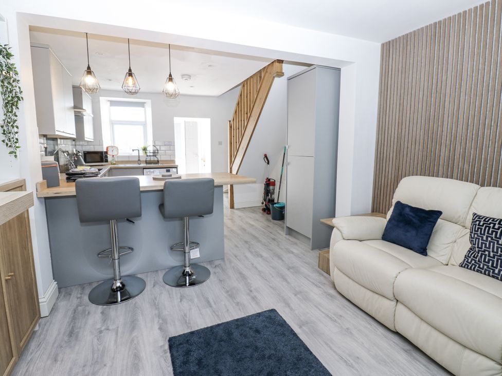 A living room with stools and kitchen area at Keekle Terrace in Cleator Moor