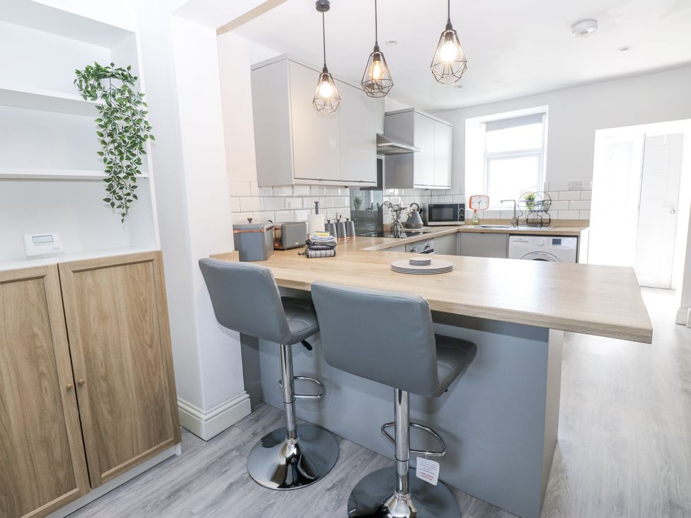 A kitchen with a countertop and bar stools at Keekle Terrace in Cleator Moor