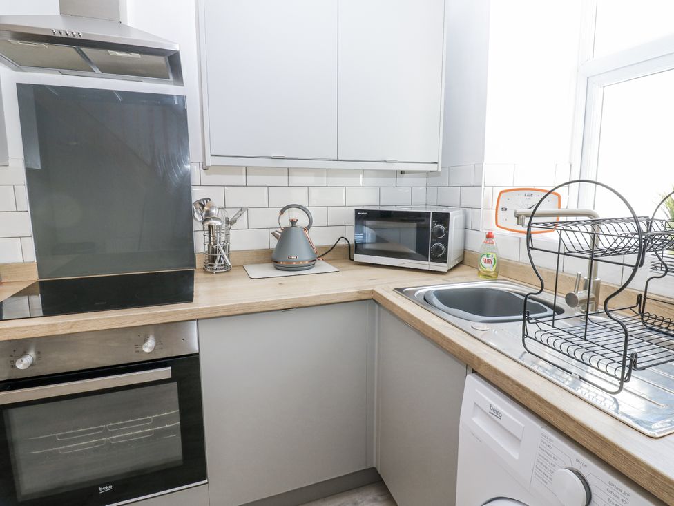 A kitchen with appliances including an oven and microwave at Keekle Terrace in Cleator Moor