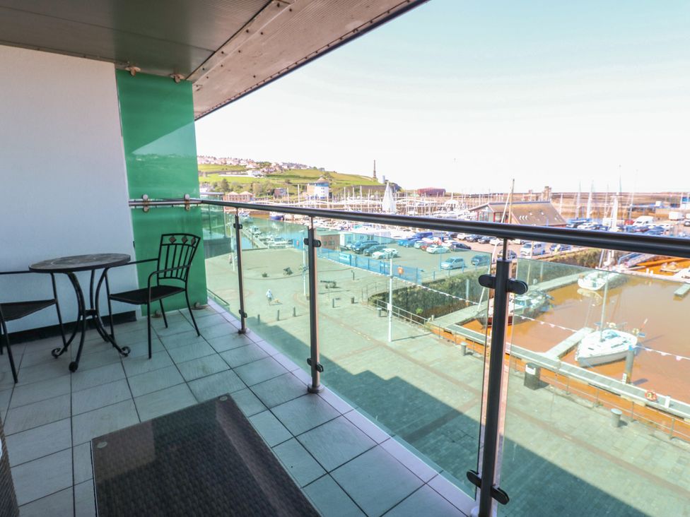 A balcony with a table and chairs overlooking a marina at Pears Suite Whitehaven