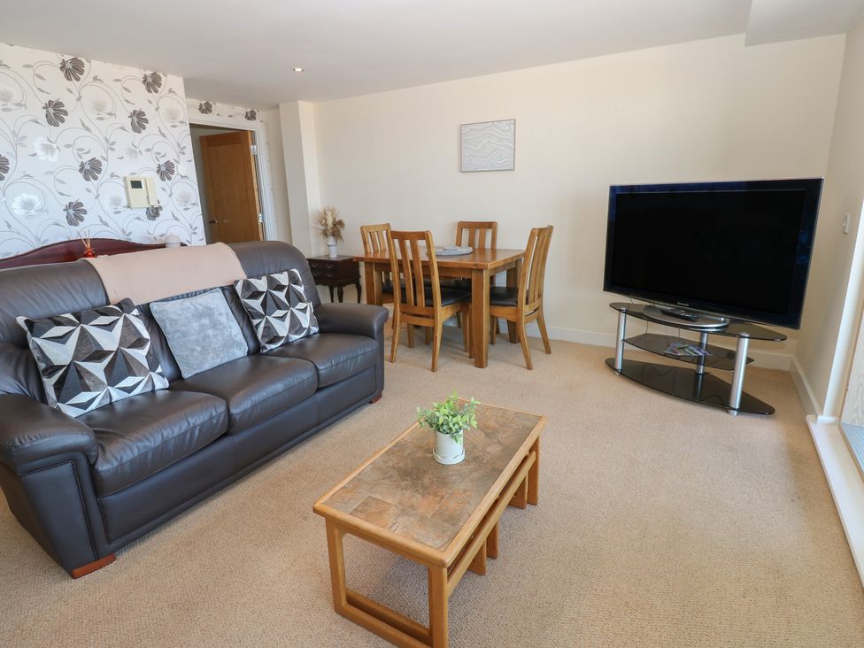 A living room with a sofa and dining area at Pears Suite in Whitehaven