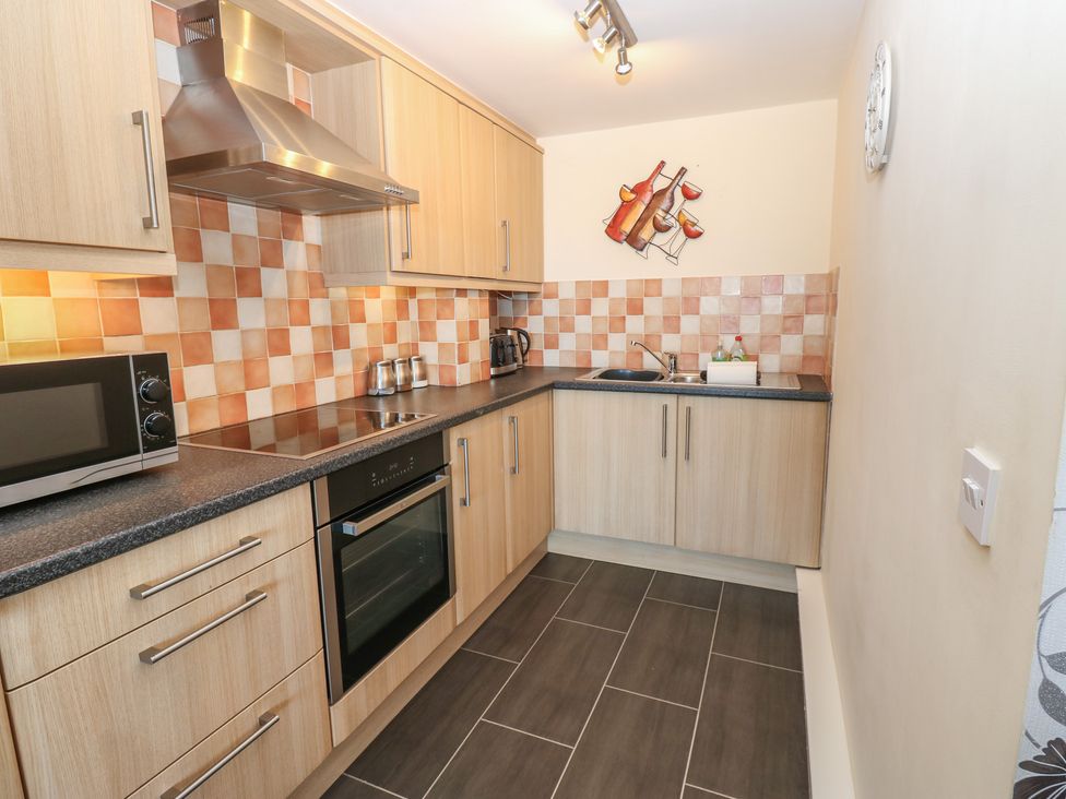 A kitchen with a stove, oven, and microwave at Pears Suite in Whitehaven