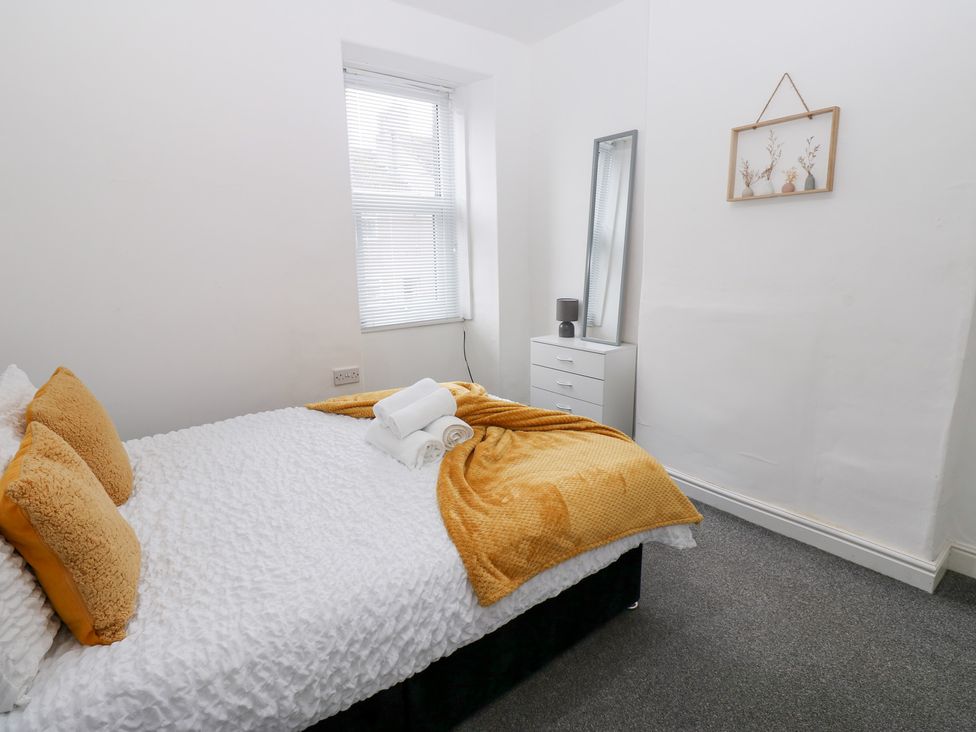 A bedroom with a bed and mirror at Holly House in Waberthwaite