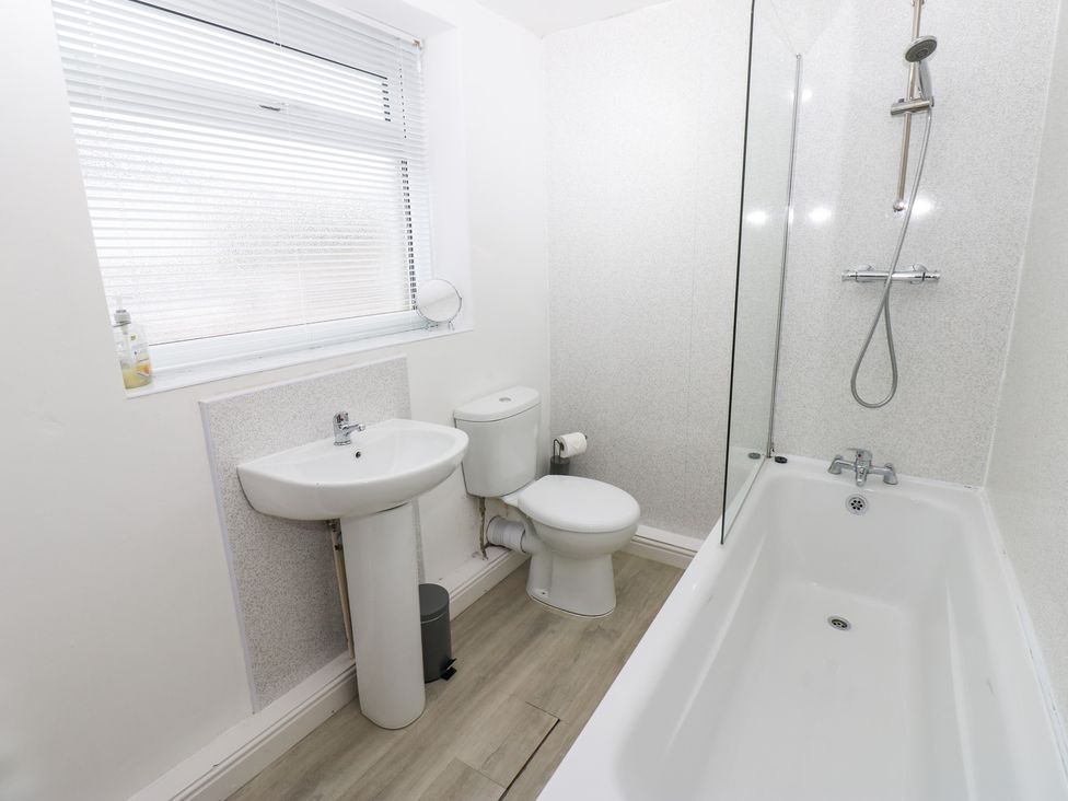 A bathroom with a bath tub, sink, and toilet at Holly House in Waberthwaite