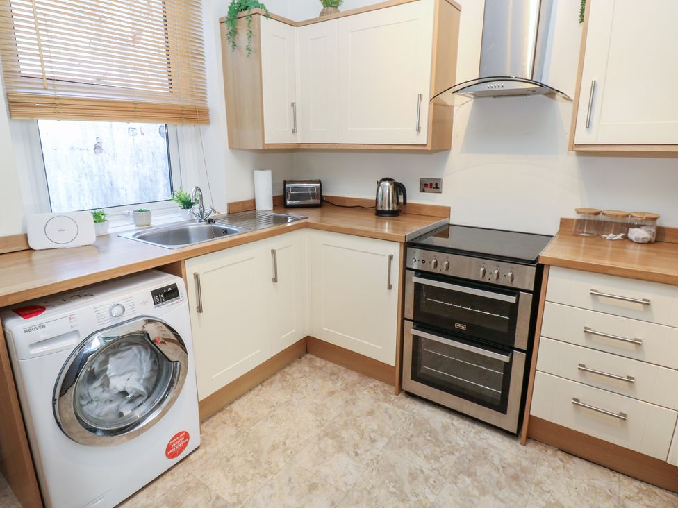 A kitchen with a washing machine, sink, kettle, and oven at Lonsdale Street