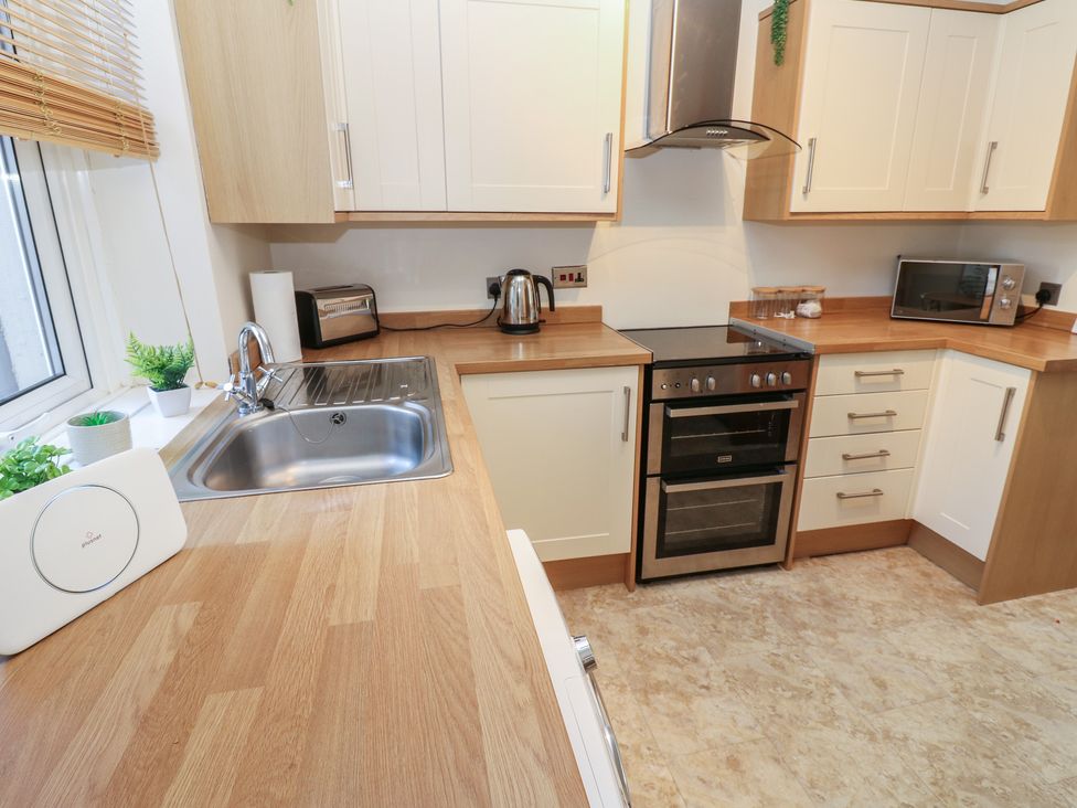 A kitchen with white cabinets, sink, oven, kettle and microwave at Lonsdale Street